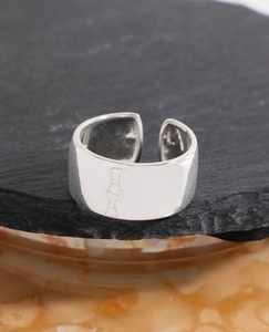 Close-up of a wide 925 sterling silver ring featuring engraved bow designs and polished finish