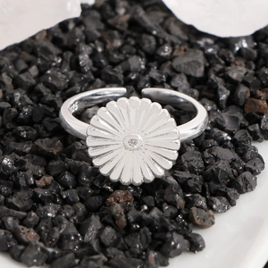 S925 sterling silver daisy ring with sparkling zircon stone on black pebble stone background