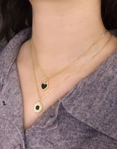 Close-up of gold double layer necklace with heart and coin pendants on purple knit