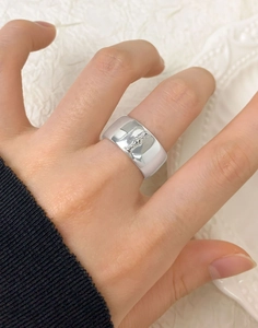 Detailed view of wide silver ring with embossed emblem on hand with white background