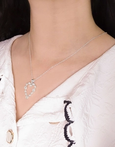 Detail view of a sparkling heart-shaped zircon pendant necklace on a model's neck