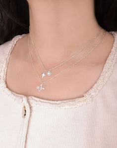 Detail of S925 silver layered necklace with star pearl and bow arrow charms on neck