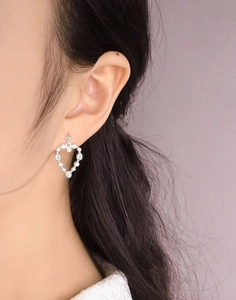 Gros plan de boucles d'oreilles cœur en argent 925 avec zircons brillants sur modèle
