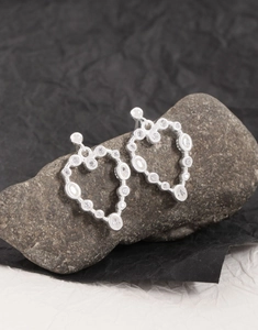 Détail macro du poinçon S925 et boucle d'oreille cœur en zircon sur pierre naturelle