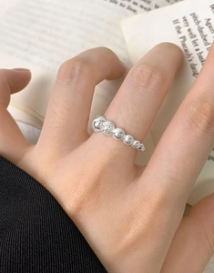 Detailed macro view of S925 sterling silver beaded ring with hammered texture on index finger