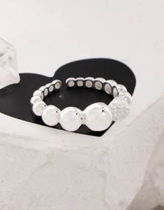 Detail of S925 sterling silver beaded ring on a black heart card against white stone