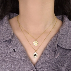 Double-layered gold necklace with star-moon relief and black onyx gemstone pendant