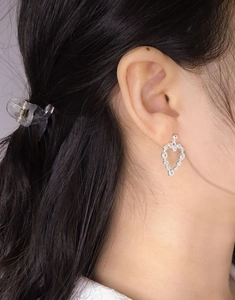 Gros plan de boucles d'oreilles cœur en argent S925 avec zircons portées par un mannequin