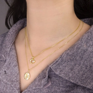 Double layer gold necklace featuring starburst coin and heart zircon pendants