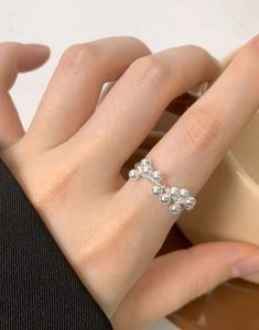 Vista dettagliata di un anello di perle in argento S925 al dito in un contesto lifestyle