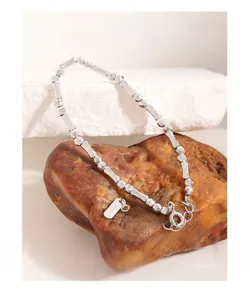Macro detail of S925 sterling silver bamboo chain bracelet on a decorative stone base