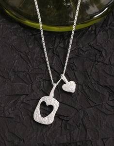 Détail macro du collier S925 en argent avec double pendentif cœur et finition martelée