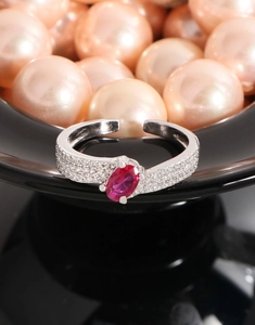 Close-up of adjustable silver ring with oval magenta zircon and micro-pave side stones