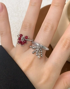 Macro detail of S925 silver ring featuring red bead floral design and pearl tassel charm