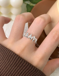 Détail d'une bague spirale en argent S925 portée à la main tenant une tasse de café