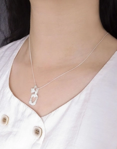 Détail du collier en argent S925 avec pendentif double cœur texturé sur le mannequin