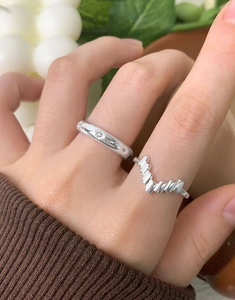 Close-up of stacked S925 silver V-shaped and star engraved rings on a finger