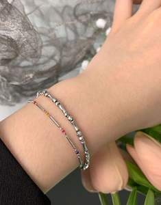 Macro view of layered S925 silver beaded bracelets with colorful accent beads on a wrist