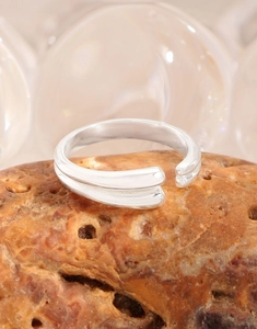 Macro shot of silver double-layered teardrop open ring on a textured natural rock