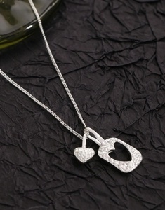 Détail du collier coeur en argent S925 avec double pendentif texturé sur fond noir