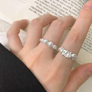 S925 sterling silver heart and beaded ring set worn against a minimalist book background