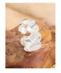Gros plan d'une bague ovale concave en argent S925 posée sur une roche naturelle brune