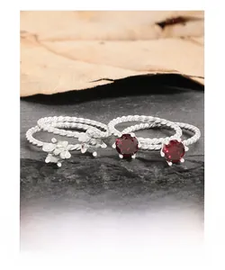 Detailed view of four S925 sterling silver rings with red zircon stones on stone base