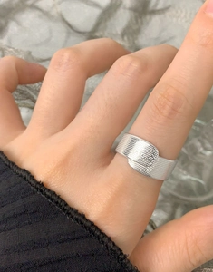 Dettaglio dell'anello a fascia in argento S925 con trama a rete sulla mano della donna