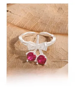 Close-up of S925 silver cherry bow ring with red stones on a rustic autumn leaf
