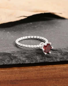 Macro shot of silver twisted rope ring featuring a six-prong set deep red zircon stone