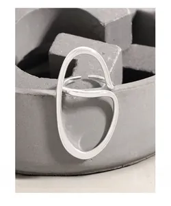 Macro shot of irregular streamlined silver ring on textured stone pedestal