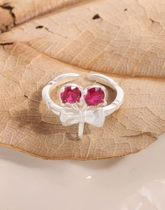 Close-up of S925 silver cherry bow ring with red stones on a dried autumn leaf