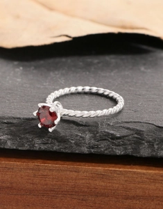 Macro shot of silver twist band ring featuring a red zircon in a classic six-prong setting
