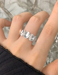 Gros plan de quatre disques ovales polis sur une bague minimaliste en argent S925