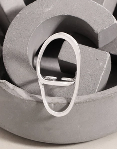 Detail of irregular silver line ring on grey geometric stand with modern minimalist style