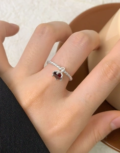 Detail of S925 silver twist ring featuring a dangling red zircon stone on finger