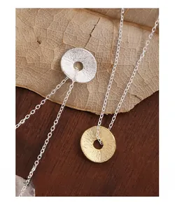 Macro detail of round textured coin pendants in silver and gold on 925 silver chains