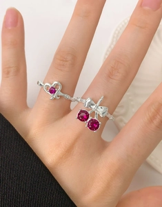 Detail of S925 silver ring featuring cherry motif and heart keyhole with red gemstones