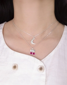 Détail d'un collier cerise en argent avec pierres roses et nœud porté par un mannequin