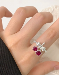Macro detail of cherry bow ring with red stones worn on finger, S925 sterling silver style
