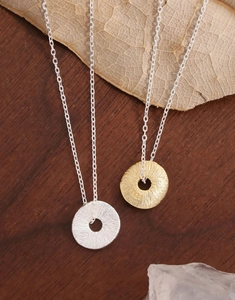 Macro detail of S925 sterling silver coin necklace with hammered texture on wooden surface