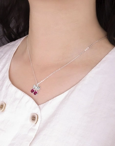 Gros plan du collier cerise en argent sterling S925 porté sur une chemise en lin blanc