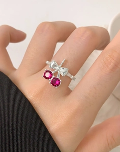 Detail shot of a silver cherry ring with red stones worn on a finger for a sweet style