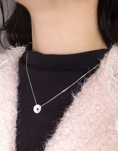 Detail of S925 sterling silver coin necklace with textured pendant on a model