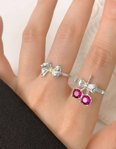 Detail of silver cherry bow ring with red corundum stones and zircon on a model's hand