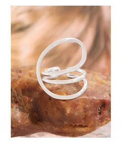 Macro detail of the curved S925 sterling silver layered open ring on a textured stone