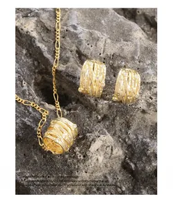 Dettagli di set collana e orecchini dorati con texture su roccia vulcanica scura