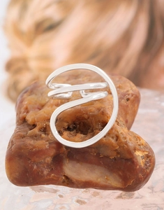 Macro detail of minimalist spiral silver ring on natural stone showing fluid lines