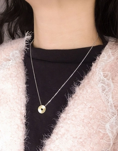 Macro view of a two-tone textured circular pendant on a delicate silver chain