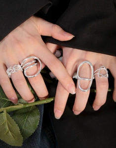 Close-up of four minimalist S925 silver rings with geometric and wavy line designs